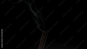 Group of smoldering or burning real red incense sticks coil with thick white smoke isolated on dark black background. Asian indian funeral, prayer, puja, spa and wellness concept. Close up side view.