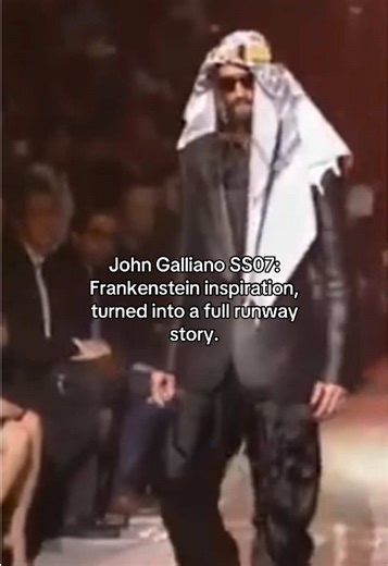 John Galliano Spring/Summer 2007 menswear was shown in Paris on June 30, 2006, and the collection was built around a Frankenstein reference. The runway was framed with gantries that “sizzled into life” with showers of sparks, setting the tone before the first looks even landed. The opening run stayed surprisingly sharp: tailored gents in shiny sharkskin suits and python-printed trenches, plus a purple coat with a chiffon back called out as a key exit look. Then Galliano pivoted hard into a surf-