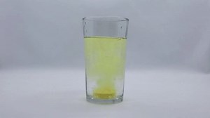 Slow motion of an effervescent supplement is dropped into a glass of water.