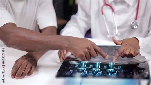 Consultation traumatologist African female doctor discussing with african male patient about MRI scan in medical clinic office, Help with back injuries, hernias and spinal protrusions.