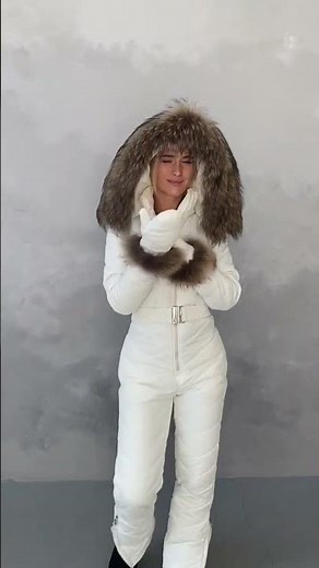 Snow-white ski jumpsuit with a hood, mittens, a belt and natural fur. Women's winter overalls.