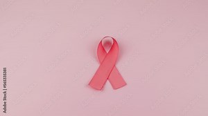 Video of Hands placing a pink Ribbon as a symbol of Cancer Awareness Month (World Cancer Day) on a pink background, space to copy.