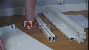 DIY white table assembly process at home. Furniture installation. New home and man assembling furniture do it yourself. Male assembling table from box according to instructions on floor.