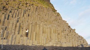 Iceland tourist woman by Reynisdrangar basalt columns on Reynisfjara black sand beach of Vik, South Iceland coast. Happy woman visiting tourist attraction destination. RED EPIC SLOW MOTION