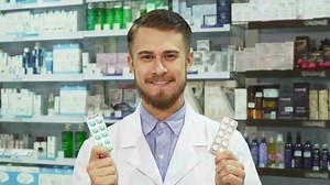 Download Young pharmacist showing medication and smiling for free