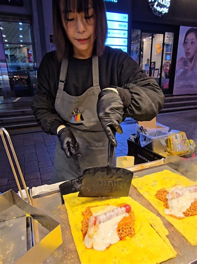 Folding Buldak Cheese Omelette — Korean Street Food 명동 길거리에서 발견한 🔥 폴딩 불닭 치즈 오믈렛! 주문 즉시 철판 위에서 펼쳐지는 계란 — 큼직한 소세지 불닭볶음면을 듬뿍 넣고 모짜렐라 체다치즈까지 올린 뒤 접어서 완성하는 퍼포먼스 오믈렛 🤤 불닭 특유의 매콤함에 치즈가 녹아내리면서 고소함 폭발… 겉은 촉촉, 속은 매콤 치즈 가득 한 입 먹으면 바로 중독되는 맛 🔥 명동 길거리 필수 먹거리 인정. 📍 명동 길거리 #불닭오믈렛 #명동길거리음식 #한국길거리음식 #치즈오믈렛 #불닭볶음면