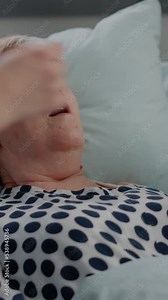 Vertical video: Close up of hyperventilating woman in hospital ward bed while doctor and nurse using oxygen tube for respiratory problem. Senior patient receiving help against breathing heavily.