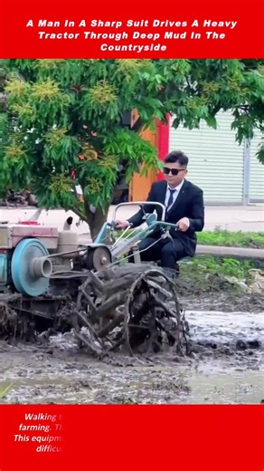 A Man In A Sharp Suit Drives A Heavy Tractor Through Deep Mud In The Countryside