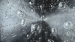 Heated water coming to the boil with rising bubbles viewed from overhead in a close up full frame view Stock Video