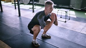 Jumping squats at gym. Effective exercises for a great fit. lunch short workout. Effective powerlifting jumps. Male fitness instructor showing squat exercise at loft plase.