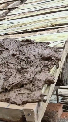 Worker Spreading Wet Mud Layer Over Wooden Plank Structure