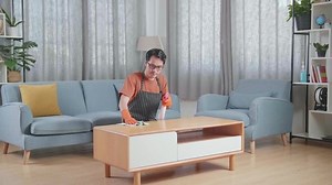 Asian Male Housekeeper With An Apron Cleaning The Table By The Spray At Home