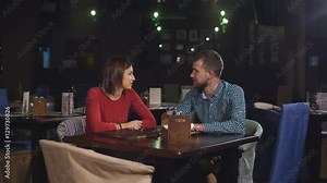 young couple sitting at a table in a cafe and talking