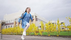 Girl child with backpack goes to school. Pupil for first time on an educational lesson. Happy little girl with backpacks runs to first lesson. The joy and smile of child. Concept of school education.