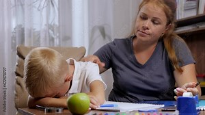 A little boy cries when doing homework at home, an angry mother shouts at the child. They are sitting at a desk with school supplies. Problems of children and parents.