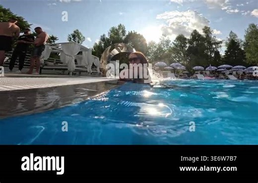 Woman relaxing in the pool near a waterfall at a luxury resort, enjoying a sunny day and refreshing water Stock Video Footage - Alamy
