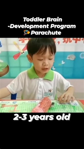 🇱🇷A parachute teaches 3 years old "High" and "Low" Today's classroom was so lively! 🌈 When the colorful "rainbow umbrella" unfolded, the whole playground lit up. The children excitedly formed a circle, their little hands gripping the edges tightly, their eyes sparkling. "Up!" the teacher shouted, and the umbrella was raised high, like a colorful cloud floating in the air ☁️. "Down!" the children lowered the umbrella again, their laughter filling the classroom like bubbles 🎶. While playing, t