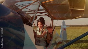 Young adventurous woman pilot in old airplane at summer sunset. Freedom, extreme and feminism concept. Breathtaking adventure in the air. Proffesional captain girl preparing for flight and skydiving