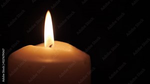 memorial candle burns on a dark background