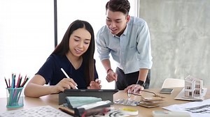 Asian Interior Architect working with architectural model choosing material and study mass model house design ideas concept.Designer group brain storming in a meeting idea for new house.