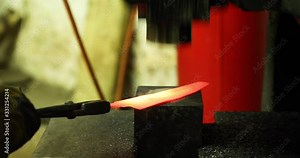 Bladesmith working with hot blade at hydraulic press