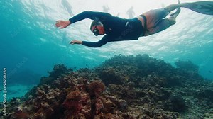 Man swims underwater in the tropical sea