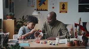 African American father and little son using paint while coloring planets on DIY solar system model at desk in kids roomAfrican American father and little son using paint while coloring planets on DIY