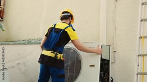 Expert technician contracted to repair broken air conditioner, dismantling condenser front coil panel to check faulty blower fan. Wireman opening hvac system to check for bad wiring