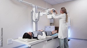 A specialist doctor in an X-ray room, a radiologist sets up a machine for radiography of a patient and makes a scan. The concept of medical technologies, modern medical equipment.