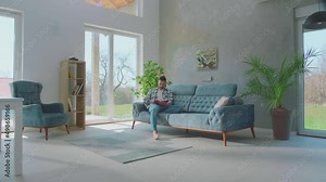 Young husband reading a book and wife joined him. Married couple reading a book together sitting on sofa at home