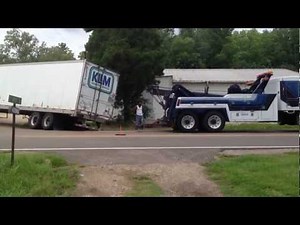 Tow truck operator in action preparing to haul out a big rig Jacknifed Trucker Accident
