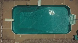 Top down view of an in ground pool with sparkling clear water on a hot day