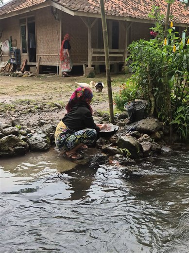 Grandmother Washing Clothes in Clear River Water