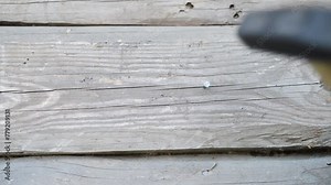 Man hammers hammering a nail into the wall of an old wooden barn.