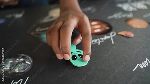 African american child doing his homework on the solar system in science class with his mother's help, hands close up
