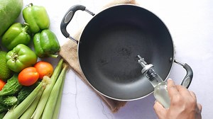 Download a person is pouring cooking oil on a frying pan for free
