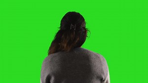 Free stock video - Close up studio rear view shot of female teacher or businesswoman facing away from camera towards green screen