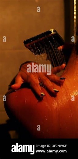 Close-up of woman enjoying warm shower with water flowing over shoulder and hand. Wellness, body care, relaxation, skincare and spa lifestyle in cinematic lighting Stock Video Footage - Alamy