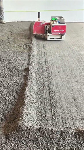 Red-and-white VASA machine smooths gravel—floor firms beneath rhythmic industrial hum
