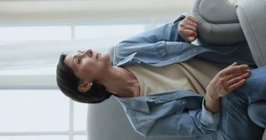 Thoughtful serious pretty senior woman sitting in armchair at home, looking out of window in deep thoughts, waiting, thinking over elderly age, retirement plans, loneliness