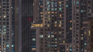Windows in high-rise building exterior in the late evening with interior lights on timelapse
