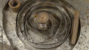 Old tools and a roll of galvanized metal tape lie on a sheet of metal with traces of rust, background, slow motion