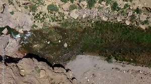 Aerial top view footage of a river as the camera tracks the water flowing gracefully through valley, capturing the nature.