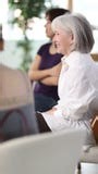 Positive mature woman sitting with other women in circle and chatting, language conversation speaking club or