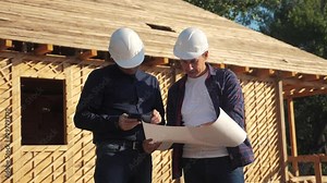 teamwork. concept building constructing architect lifestyle slow motion video. two men builder in helmets study digital tablet the house plan. two architects working on construction of frame house