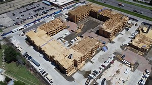 Large urban apartment building under construction, busy workers and construction machines working near Interstate I-35E Stemmons Freeway Dallas, Texas, timber wood frame, elevator vertical shaft