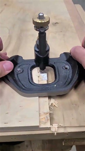 A mortising chisel attached to a router base cuts a square hole in a piece of wood