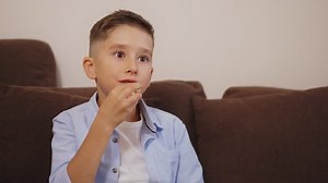 Cute little boy eating popcorn while watching TV, leisure time after school