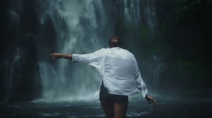 Back of woman woman in straw hat enjoying breathtaking high waterfall Sekumpul with rain in Bali rainforest. Great wild nature of Indonesia