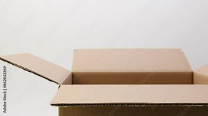 Hands takes a stone with FAKE line from a cardboard box. On a white background. Isolated. Fake delivery concept. Wrong delivery concept. Stock Video